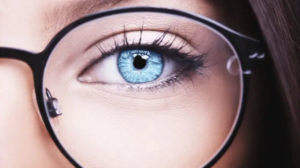 Close-up of a blue eye behind a pair of round black eyeglasses