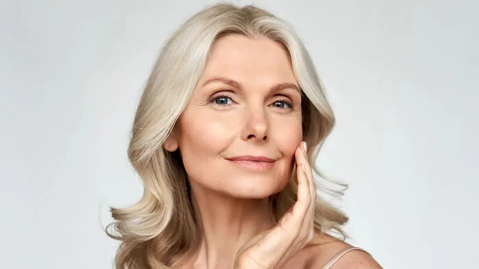 Woman with silver-blond hair resting her fingers on her cheek